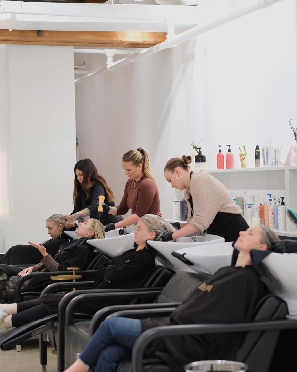 A row of wash basins with stylists working