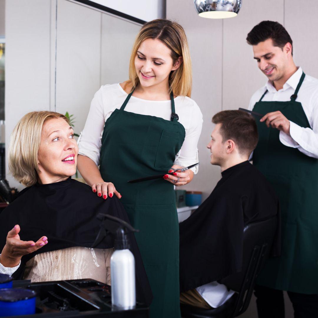 Two stylists cutting, customers gowned in the chairs