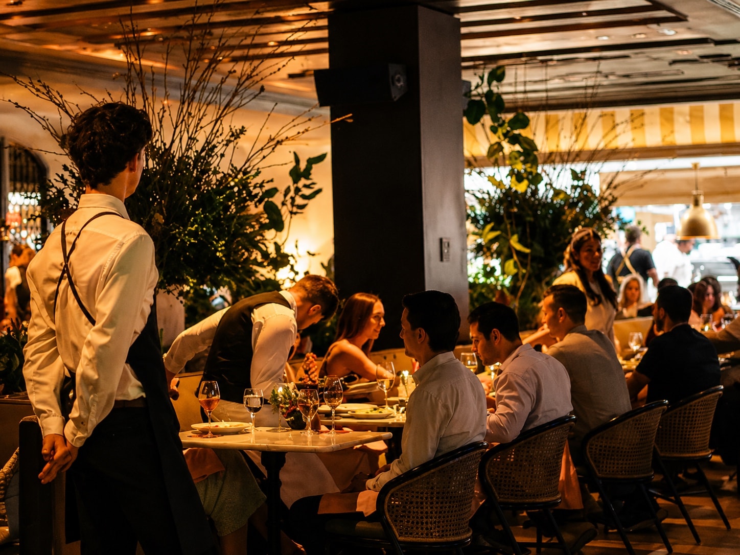A busy room of small tables, glasses and warm light