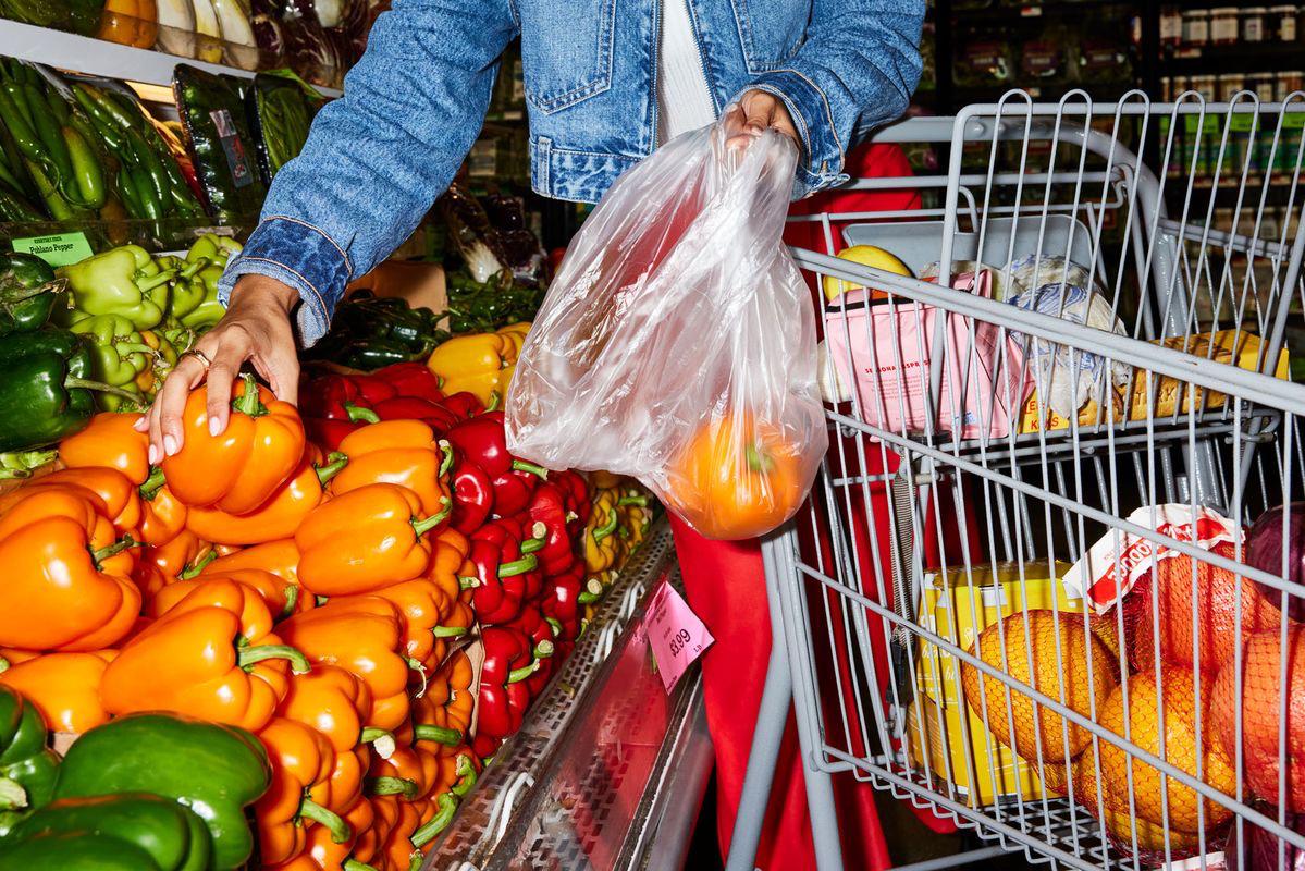 Choosing peppers from a produce display beside a trolley